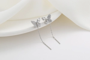 Detail of silver butterfly tassel earrings with micro-set zircon on white ceramic