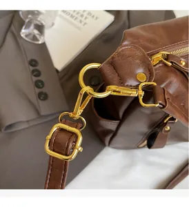 Detail of premium golden hardware and brown textured leather on an underarm tote bag