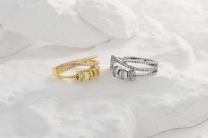 Detail of gold and silver rotating zircon rings with crisscross layers on white stone