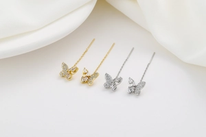 Detail view of gold and silver butterfly tassel earrings with sparkling zircon stones