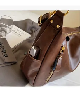 Detail of brown leather tote side pocket with gold studs and functional side zipper