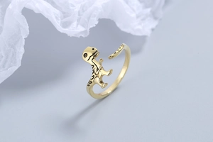 Detailed view of adjustable golden dinosaur ring with black enamel stripes on a blue base