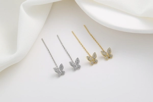 Close-up of butterfly tassel earrings with pavé zircons in silver and gold finishes