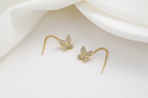 Macro detail of gold butterfly tassel earrings with sparkling micro-pave zircons