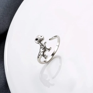 Close-up of adjustable silver dinosaur ring featuring a cute T-Rex on a white ceramic plate