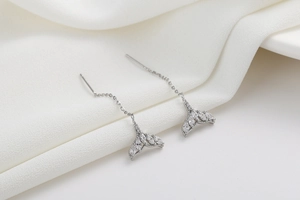 Detail of mermaid tail tassel earrings with marquise-cut zircons on a soft fabric backdrop