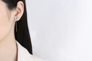 Close-up of long silver butterfly tassel earrings with sparkling crystals on a model