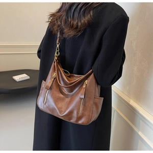 Close-up of brown matte leather tote bag with vertical zippers and gold hardware detail