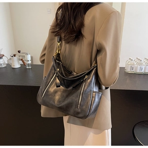 Detail of black leather hobo shoulder bag with gold hardware and side pockets