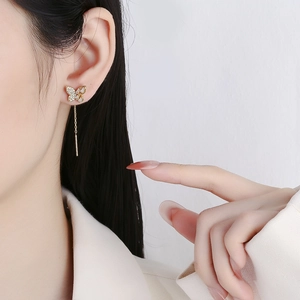 Elegant butterfly tassel earrings in gold with sparkling zircons worn by a model
