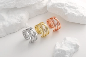Close-up of criss-cross rings in silver, gold and rose gold with micro-paved zircon stones