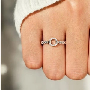 Silver infinity circle ring with sparkling zircon stones on female hand with white knit