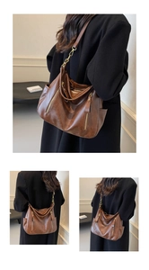 Detail view of brown leather shoulder bag with vintage metal zippers and texture