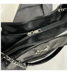 Close-up of smooth silver zipper and crackled leather texture on black tote bag