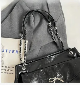 Close-up of black tote bag featuring a silver bow buckle and metal chain strap details