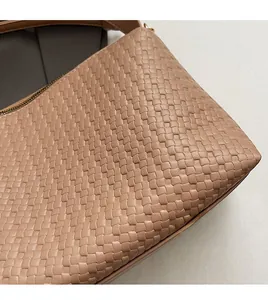 Détail de la texture en cuir tressé rose et fermeture éclair dorée sur le sac Boston