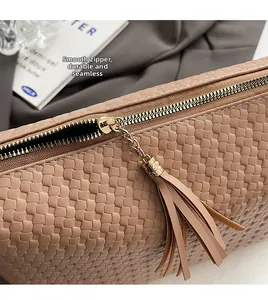 Détail du sac Boston tressé beige avec fermeture éclair dorée lisse et pompon en cuir
