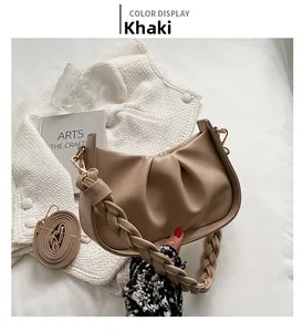 Détail du sac demi-lune plissé kaki avec bandoulière tressée et attaches métalliques dorées