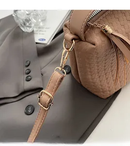 Détail de la texture en cuir marron tressé et du crochet en métal doré amovible