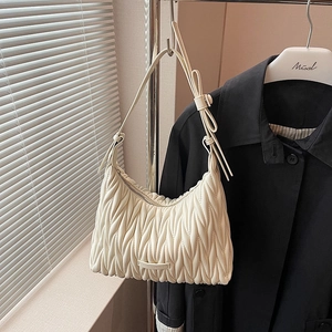 Close-up of cream pleated leather texture and knot detail on a fashion hobo bag