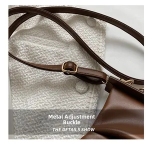 Vue macro d'une bandoulière en cuir marron avec boucle en métal doré réglable du sac