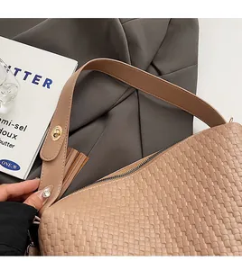 Gros plan sur la texture tissée d'un sac Boston beige avec une poignée en cuir