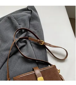 Detail of adjustable long shoulder strap with gold hardware on brown bucket bag