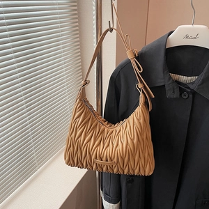 Detailed view of caramel pleated leather texture and metallic logo on shoulder bag