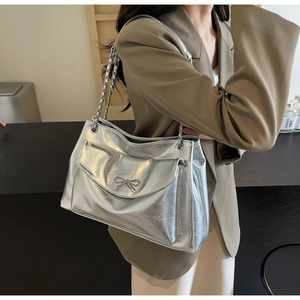 Close-up of metallic silver tote bag with crackle texture and metal bow detail