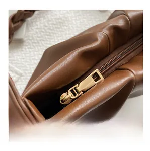 Détail du sac plissé en cuir marron foncé avec fermeture éclair dorée et anse tressée