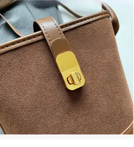 Close-up of brown suede bucket bag featuring polished gold metal clasp and leather trim