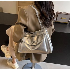 Silver metallic tote bag with bow detail and chain strap styled on a model outfit