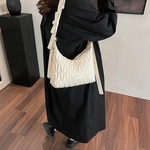 Detail of a beige pleated leather hobo bag with side bow design shown on a model