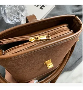 Close-up of smooth golden metal zipper and hardware on brown suede bucket bag
