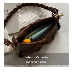 Détail d'un sac en cuir PU marron foncé montrant l'intérieur spacieux et la poignée tressée