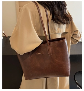 Detail of a dark brown vintage tote bag showing its rich leather texture and metal logo