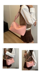 Détail du sac bandoulière rose tressé avec pompon assorti et finitions dorées chic