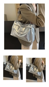 Detailed shot of silver tote bag with metallic bow and chain strap on shoulder
