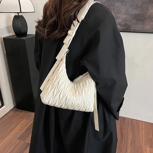 Close-up of white matelassé pleated leather moon bag with metallic logo detail