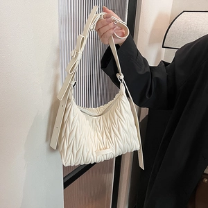 Detailed view of white pleated leather texture and bow detail on the shoulder bag