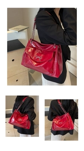 Detail of red patent leather shoulder bag with bow hardware and chain strap accents