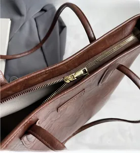Macro detail of the smooth golden zipper and brown faux leather tote bag with lining