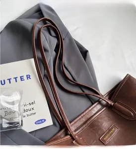 Detail of dark brown leather tote bag showing vintage texture and zipper closure