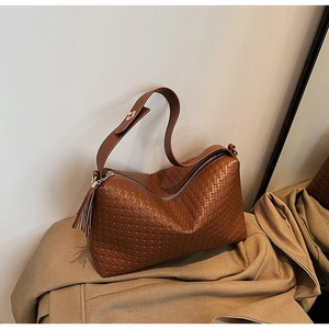 Détail d'un sac en similicuir tressé marron avec pompon et fermeture éclair