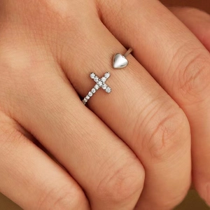 Gros plan d'une bague ajustable en argent avec cœur et croix en zircone portée