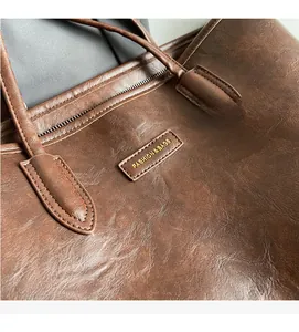Close-up of a dark brown leather tote bag featuring a gold Fashion & Bags logo detail
