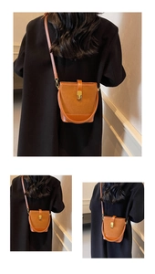 Detail of brown leather bucket bag with gold clasp shown on a crossbody model