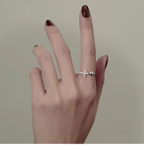 Détail d'une bague ouverte en argent avec croix pavée de zircons et décor cœur poli
