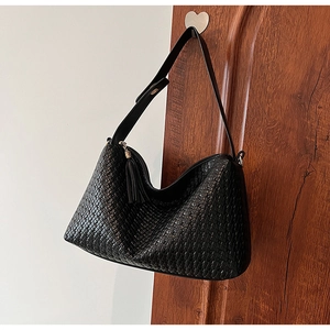 Détail d'un sac porté épaule en cuir tressé noir avec texture fine et gland