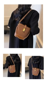 Detail of a brown bucket bag showing the suede leather texture and gold metal twist lock